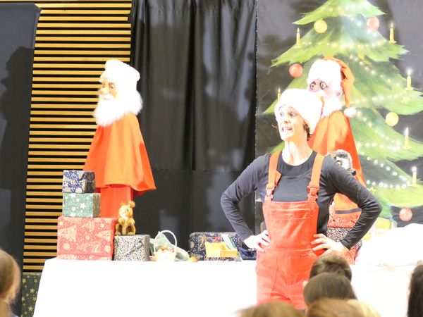 Foto aus dem Kindertheater "Der kleine Weihnachtsmann" mit einer Schauspielerin mit roter Latzhose und Mütze.